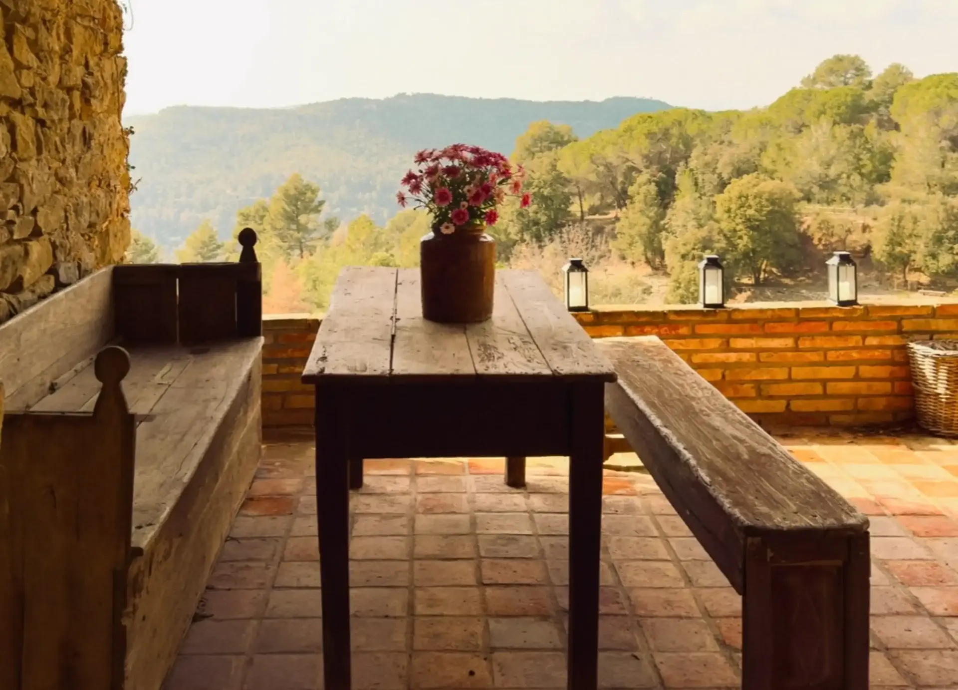 Bancos de madera y mesa rústica con flores frente a la montaña