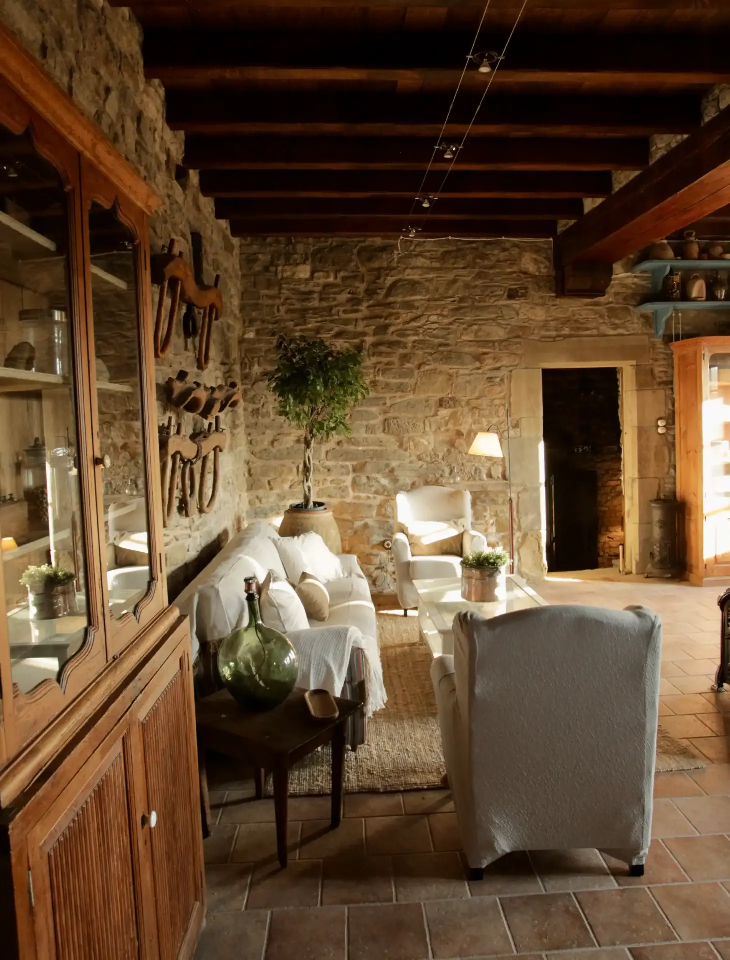 Salón rústico de piedra con sofás blancos y vigas de madera